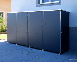 The image shows a set of three large, dark-colored outdoor storage cabinets placed next to a building. The cabinets have multiple vertical panels and are likely used for storing tools, packages, or other outdoor equipment. They are positioned on a patio or paved area.