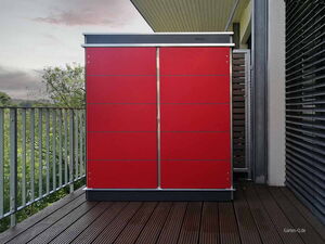. Roter Gartenschrank auf einem Balkon mit Holzplankenboden, Geländer und modernem Design im Hintergrund.