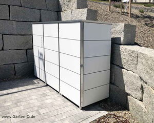 Weiße Gartenbox neben einer Steinmauer auf gepflastertem Boden.