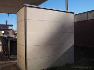 . Auf der Terrasse steht ein moderner Gartenschrank neben einem Tisch mit Stühlen.