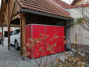 . Ein rotes Gartenhaus neben einem Carport mit einem weißen Auto darunter.