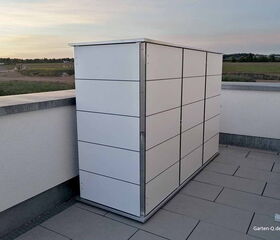 Weißer Gartenschrank auf einer Terrasse mit ländlicher Aussicht im Hintergrund.
