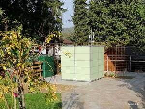 . Ein Gartenschrank in einem gepflegten Garten, umgeben von Bäumen und Pflanzen, mit gepflastertem Boden.