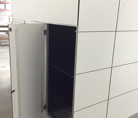 Ein geöffneter, weißer Schrank oder Raum mit quadratischen Paneelen, die einen dunklen Innenraum zeigen.