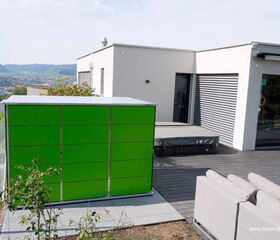 . Moderne Terrasse mit grünem Schrank, Sofa und Blick auf Stadt und Hügel im Hintergrund.