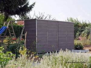 . Garten mit grauem Schuppen, Pflanzen, Schaukel und blauer Rutsche im Hintergrund.