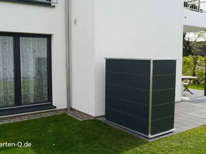 . Außenbereich eines Hauses mit Terrassentisch, Pflanzenkübel und einem modernen, dunkelgrauen Gartenschrank.