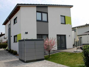 . Modernes zweistöckiges Haus mit Pultdach, weiß-grauer Fassade, kleinem Garten, Schuppen und Terrasse.