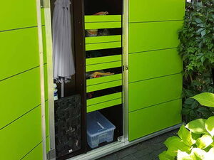 . The image shows a green outdoor storage cabinet with open doors. Inside, there are various items organized on shelves, including a plastic storage box, a hanging garment, and some other supplies. The cabinet is surrounded by greenery.