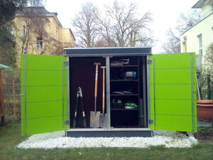 . This is an image of an outdoor storage cabinet or shed with open doors. Inside, there are various garden tools and equipment:

1. A pair of loppers.
2. A shovel and a spade.
3. Shelving on the side with other items, possibly including gardening gloves, a small toolbox, and other miscellaneous supplies.

The cabinet is placed on a bed of white stones and is surrounded by grass and trees. The doors are bright green.