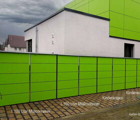Grüne Anlage mit 1.100-Liter-Müllcontainern und Kinderwagenstellplätzen vor einem Gebäude.