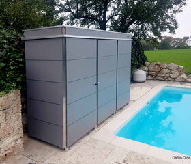 Ein grauer Gartenschrank neben einem Pool im Freien, umgeben von Bäumen und einer Steinmauer.