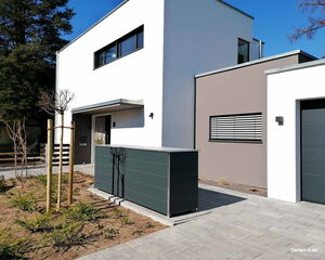 Modernes Haus mit flacher Architektur, Vorgarten mit Pflanzungen und Baum, graue Garage.