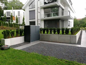 . Moderne zweigeschossige Häuser, gepflegter Garten, Sträucher, graue Steinwege, Rasenmäher auf Gras.