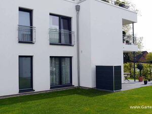 . Modernes weißes Gebäude mit drei Stockwerken, Balkon und gepflegtem Rasen.