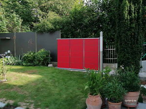 . Ein Garten mit rotem Schuppen, Topfpflanzen und grünem Rasen.