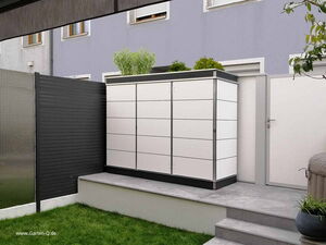 . The image shows an outdoor storage unit placed on a small platform, next to a door and some fencing. The storage unit is rectangular with a sleek, modern design, and has plants on top. There are stairs leading up to the platform, and the surrounding area includes a lawn and some potted plants. The wall behind the setup is painted gray, and the entire scene appears to be in an outdoor patio or garden setting.