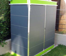 . The image shows a modern-looking outdoor storage unit. It has a sleek design with dark gray panels and bright green accents at the top and bottom. The top seems to have a small planter section with plants growing in it. It's set on a lawn near a fence and some foliage.