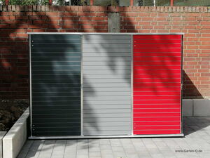 . Ein moderner Garten- oder Geräteschuppen mit drei Abschnitten (schwarz, grau, rot) vor einer Ziegelwand.