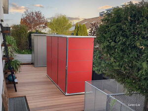 . Ein moderner Garten mit Holzterrasse, roten Schränken, Pflanzen und Metallgehege.
