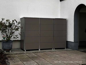 . Ein grauer Gartenschrank neben einer weißen Wand, mit einem Pflanzenkübel daneben.