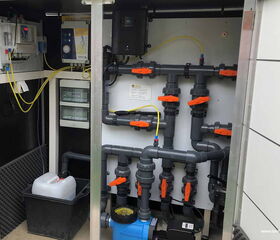 . Dieses Bild zeigt eine technische Installation mit Rohren, Ventilen und elektrischen Komponenten in einem Schrank.