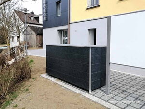 . Modernes Gebäude mit grauer Fassade und seitlichem Weg im Außenbereich.