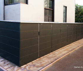 Große, moderne Gartenbox oder Schuppen neben einem Haus, dunkelgrau, auf Betonboden.