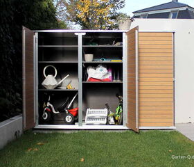 . Ein offener Gartenschrank mit Gießkanne, Spielzeug, Pflanzentöpfen und Gartengeräten auf Rasen.