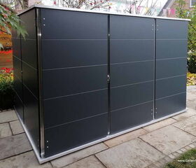 . Ein modern aussehender Gartenschuppen aus Metall befindet sich auf einer Terrasse.