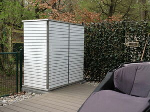 . Terrasse mit Rattan-Liegestuhl, Metallschrank, Holzboden und Efeuwand im Hintergrund.
