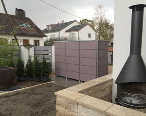 Ein moderner Garten mit Kamin, Pflanzen, einem Schuppen und angrenzenden Häusern.