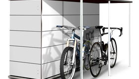 . Ein Fahrradunterstand mit einem großen, weißen Schrank und zwei abgestellten Fahrrädern.