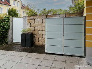 . Moderne Gartenmauer mit schwarzem Pflanzenkübel und weißer Tür auf gepflastertem Hof.