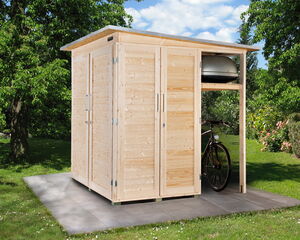 The image shows a wooden outdoor shed situated on a tile platform in a garden setting. The shed has double doors and a small overhang area where a bicycle is partially visible. There appears to be storage space above the bicycle. The surrounding environment includes grass, trees, and bushes.