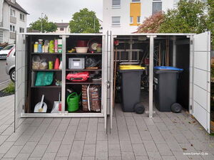 . The image shows an outdoor storage cabinet with two compartments. The left compartment contains various items like gardening supplies, cleaning tools, bags, a watering can, and other miscellaneous items on shelves. The right compartment has two large bins with yellow and blue lids and lawn equipment like shovels and rakes.