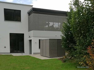 . Moderner Anbau mit Terrassenbalkon, großer Fensterscheibe und angrenzendem Garten, plus rechteckiger Struktur.