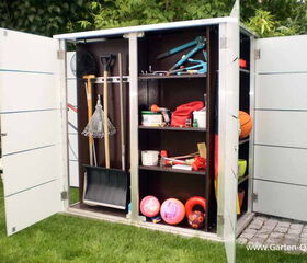 . The image shows an outdoor storage cabinet with open doors. Inside, there are various gardening tools like rakes, shovels, and a broom. Shelves hold miscellaneous items such as a garden hose, gloves, plant pots, and other small gardening tools. There are also sports items like balls and possibly outdoor toys.
