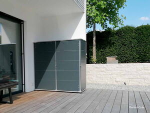 . Moderne Gartenschrank auf einer Terrasse mit Holzboden, im Hintergrund grüne Hecke und Baum.