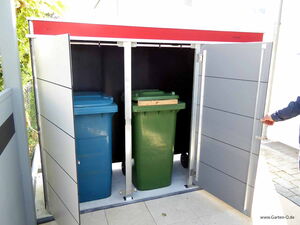 . The image shows an outdoor storage unit with open doors, revealing two large wheeled trash bins. One bin is blue, and the other is green. The storage unit has a red and gray exterior.