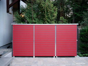 . The image shows a red outdoor storage unit or shed with horizontal slats, situated on a tiled patio area. It is positioned against a wall with greenery like bushes and trees in the background.