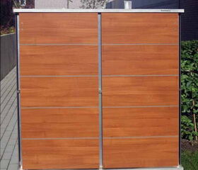 . The image shows a wooden garden shed or storage unit with a sleek, modern design. It appears to have horizontal panels and is situated on a tiled pathway, with some vegetation around it.