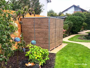 Ein Holzschuppen in einem Garten mit Pflanzen, geschwungenem Weg und blauer Dekoration.