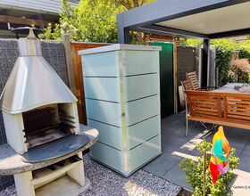 Gartengrill, Aufbewahrungsschrank, Tisch mit Holzbank, bunte Windmühle im Gartenbereich.