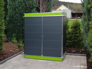 . Ein graues Gartenschrank-Modell mit grünem Akzent, umgeben von Bäumen auf gepflastertem Boden.