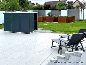 . Ein moderner Gartenschuppen auf einer Terrasse mit Liegestühlen und Hochbeeten im Hintergrund.