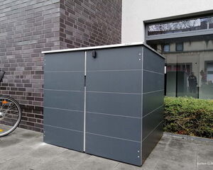 Ein moderner Metall-Geräteschrank steht neben einer Backsteinmauer und einem Fenster, mit einem Fahrrad daneben.