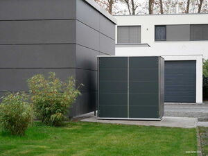 . Ein moderner Garten mit Rasen, Sträuchern, grauem Schuppen und einem zeitgenössischen Gebäude im Hintergrund.