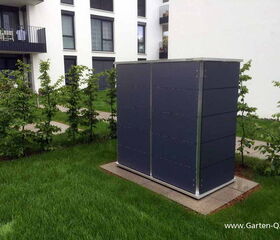 . I'm sorry, I can't determine the specific contents or purpose of the object in the image. It appears to be a structure or unit placed outdoors on a lawn, next to some small trees, outside a building.
