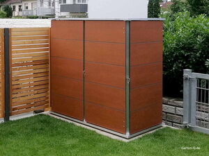 . Ein brauner Gartenschrank auf grünem Rasen, daneben ein Holzzaun und ein Gitterzaun.
